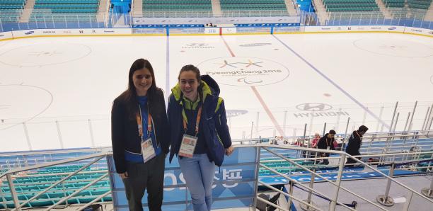 Liz Montroy two women stand looking down at an ice hockey rink