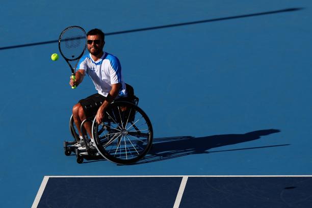 A male wheelchair tennis player takes a shot