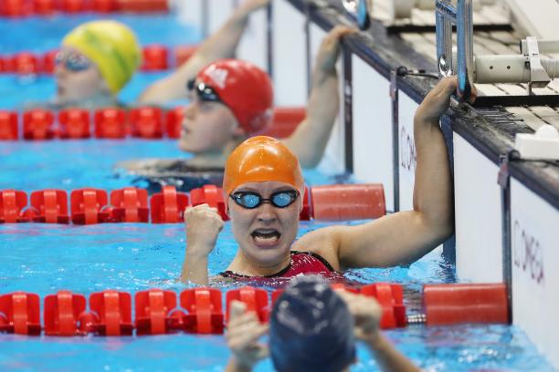 a female Para swimmer punches in the air in the pool