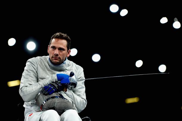 Pierre Mainville a male wheelchair fencer holding a foil and his helmet