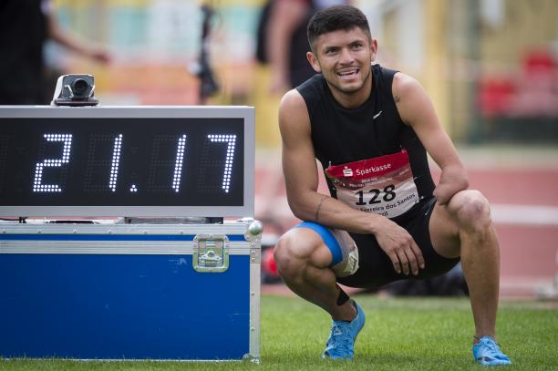 a male Para sprinter stands next to a race clock