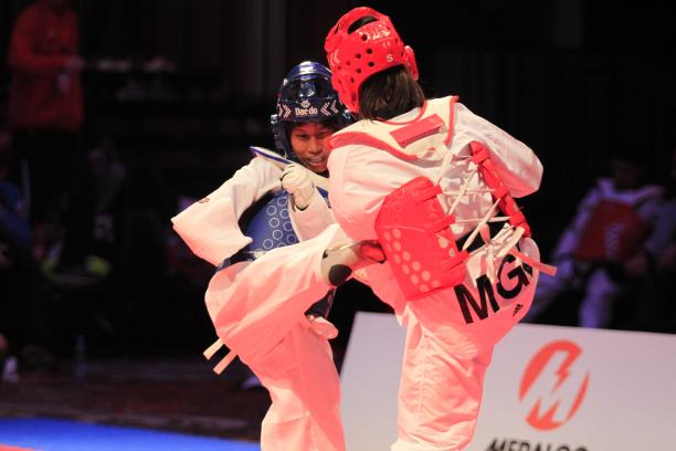 A taekwondo athlete kicks her female opponent 