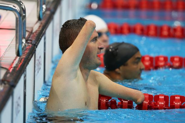 male Para swimmer Zsolt Vereczkei raises his arm in the water