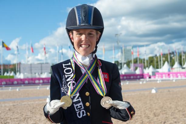 Erin Orford female Para equestrian rider Erin Orford smiles and holds up two gold medals around her neck