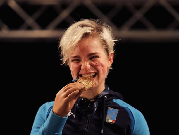 female wheelchair fencer Beatrice Vio bites a gold medal and smiles