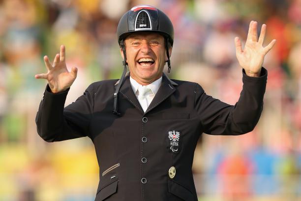 male Para equestrian rider Pepe Puch smiles and raises his hands in celebration