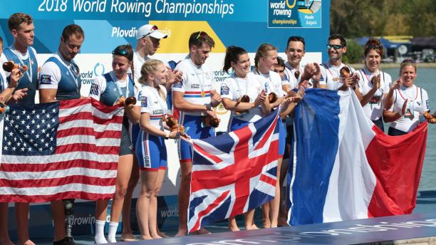 Group of female and male rowers on the podium with USA, Great Britain and France flags