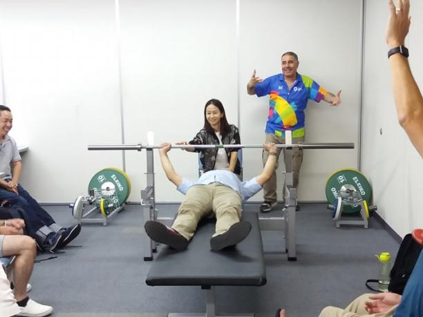 Powerlifting technical course at Kitakyushu 2018 an official tries out the weight of a powerlifting bar while lying on the bench