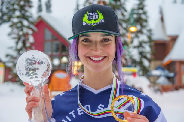 a female snowboarder holds up a crystal globe and medal