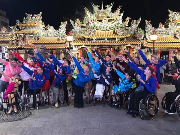 Para dance in Chinese Taipei a group of Para dancers raising their arms in front of three golden Chinese temples