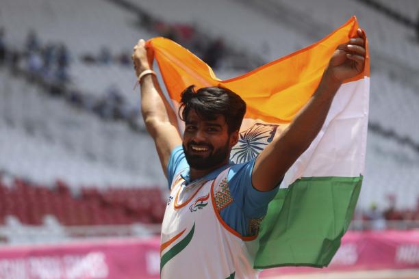 Sandeep Sandeep - Indonesia 2018 male Para athlete Sandeep Sandeep smiling and holding up an India flag
