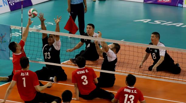 male sitting volleyball players from China and Kazakhstan volleying the ball over the net