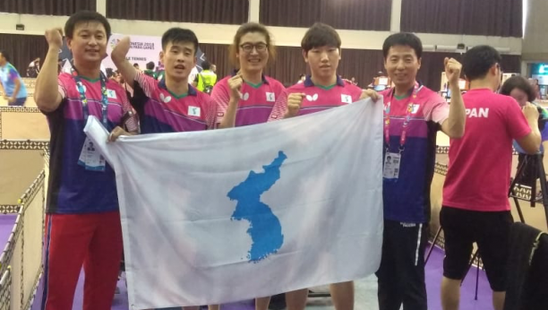 Unified Korean table tennis team - Indonesia 2018 a group of Korean table tennis players standing with a United Korea flag
