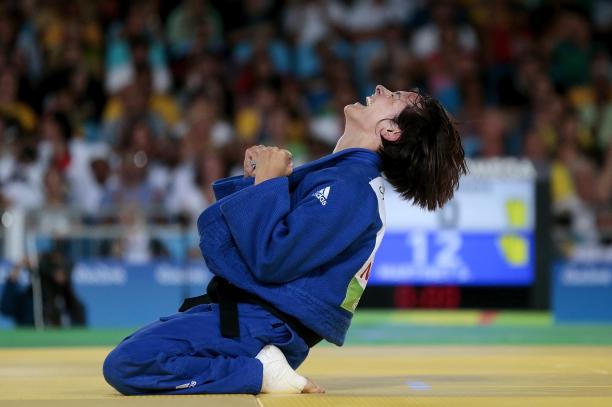 female judoka Sandrine Martinet sinks to her knees and clenches her fists after winning