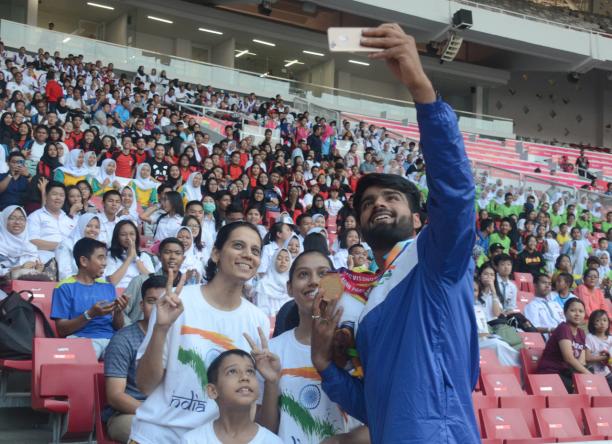 Sandeep Chaudhary - India - Para athletics - Asian Para Games 2018 Man with a medal taking pictures with fans on the stands in a stadium