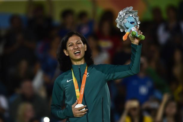 female judoka Lucia Araujo smiles on the podium holding up a mascot 