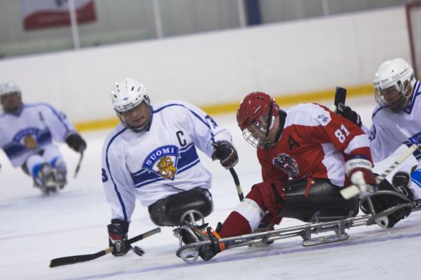 male Para ice hockey player Markku Hirvela defends the puck from a Polish player