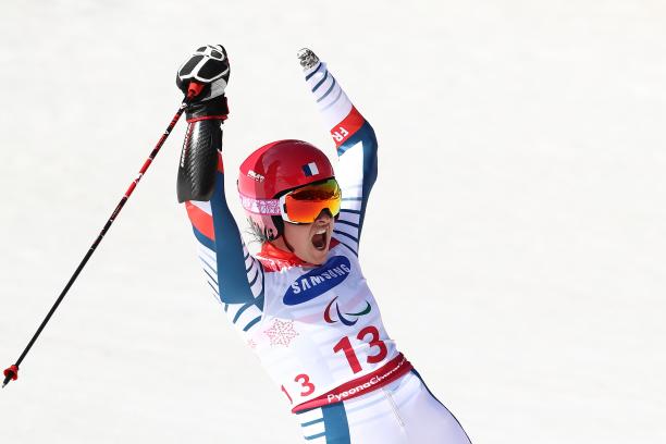 female Para alpine skier Marie Bochet raises her arms on the slopes after crossing the finish line
