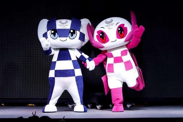 the two mascots for the Tokyo 2020 Olympic and Paralympic Games holding hands on stage