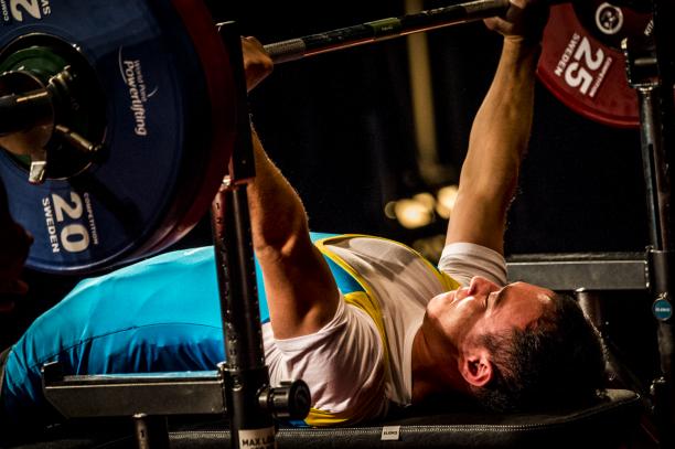 a male powerlifter from Kazakhstan on the bench