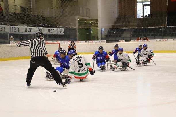 Two referees, three Italian and five South Korean Para ice hockey players on ice 