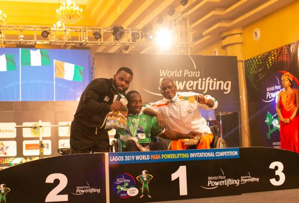 Nigeria powerlifting - Mufutau Rasaq three male powerlifters, with Mufutau Rasaq in the middles, link arms on the podium