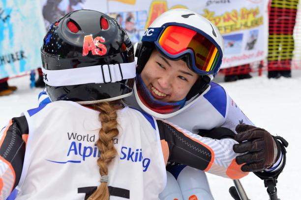 Momoka Muraoka - Alpine Worlds 2019 female Para alpine skier Momoka Muraoka hugs another female skier and smiles