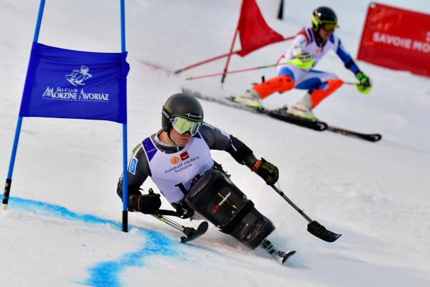 male sit skier Jesper Pedersen races head to head with a standing skier