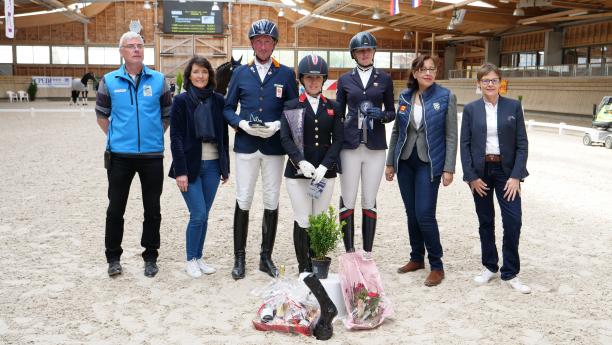 A group of people standing on a dressage arena