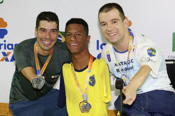 three male Para swimmers with their medals on the podium