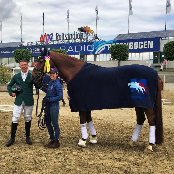Brazilian Para dressage rider posing with his horse and a staff member for a photo