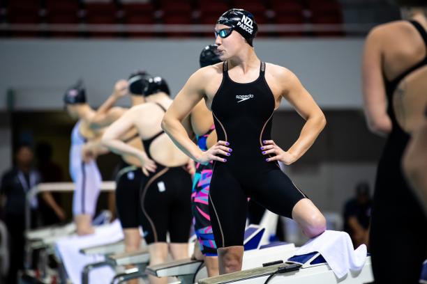 New Zealand female swimmer puts hands on hips and prepares to take her mark in pool