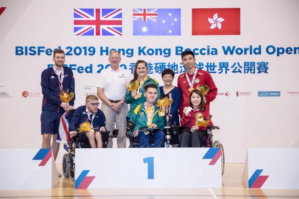 Podium photo with three boccia players and their assistants posing for a photo