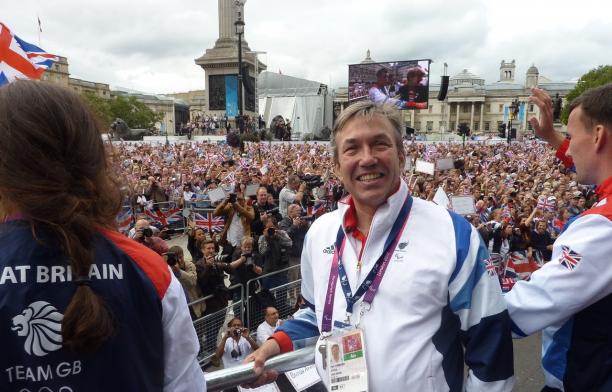 British man in wheelchair smiling in front of a big crowd of people