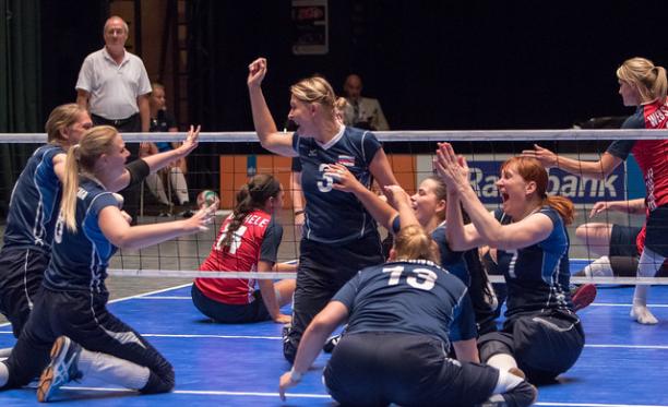 Russian sitting volleyball players celebrate together on the court after a point