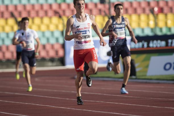 A male sprinter runner ahead of two other competitors