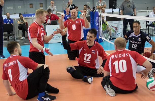 Russian men's sitting volleyball players celebrate on the court after scoring a point