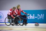A picture of 2 person in wheelchairs playing curling