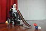 A picture of a girl in an electric wheelchair holding a small ramp.