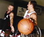 A picture of 2 men in a wheelchair playing basketball