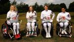 Four people in fencing suits and wheelchairs pose with their foils/epees