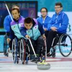 Woman throwing a stone in wheelchair curling.