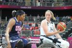 Two women in wheelchairs, playing basketball, fighting for the ball
