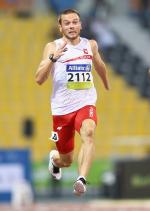a male running wearing a white top and red shorts