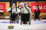 Wheelchair curler on the ice with team in the background