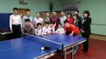 Group picture of kids and adults around a table tennis table