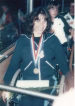 Photo of a woman in a wheelchair with a medal around her neck. The photo looks very old