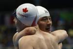 Xu Qing (R) of China is embraced by Nathan Clement (L) of Canada after winning the gold medal in the Men's 50m Butterfly - S6