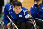 An athlete in a wheelchair competing in a game of curling. 
