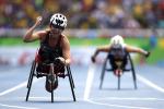 Woman in racing wheelchair crossing a finish line, celebrating